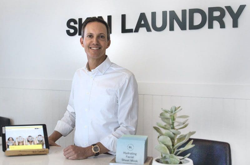 a man standing in front of a sign that says shin laundry