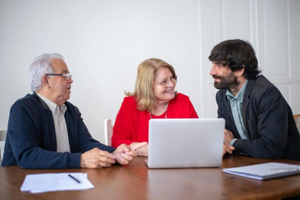 Employees discuss the business technology while working on a laptop.