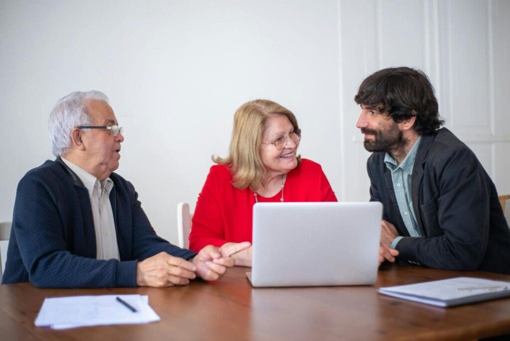 Employees discuss the business technology while working on a laptop.