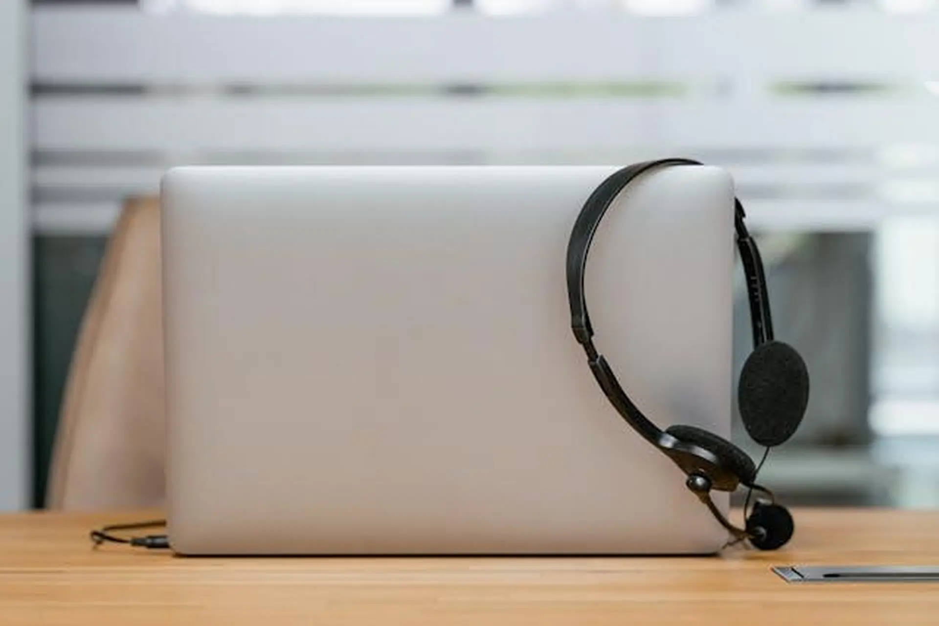 A contact center headset hanging on the edge of an open laptop’s screen A contact center headset hanging on the edge of an open laptop’s screen.