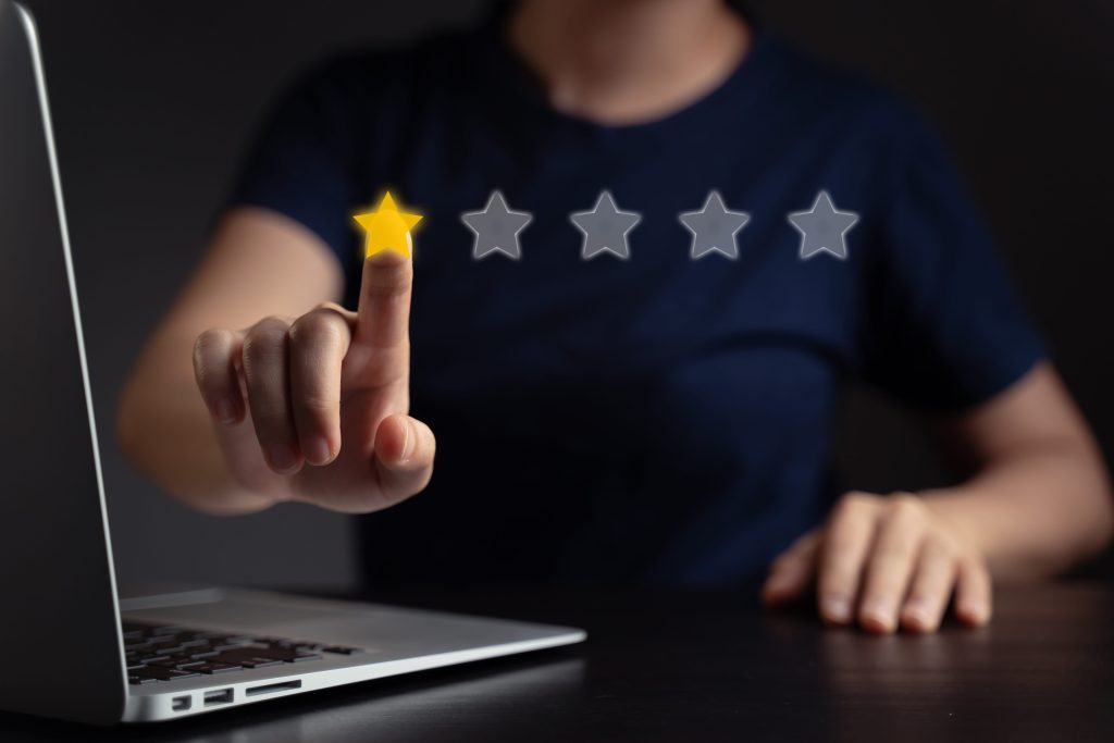 A business owner using a laptop while selecting a 1-star rating on a virtual customer feedback review screen